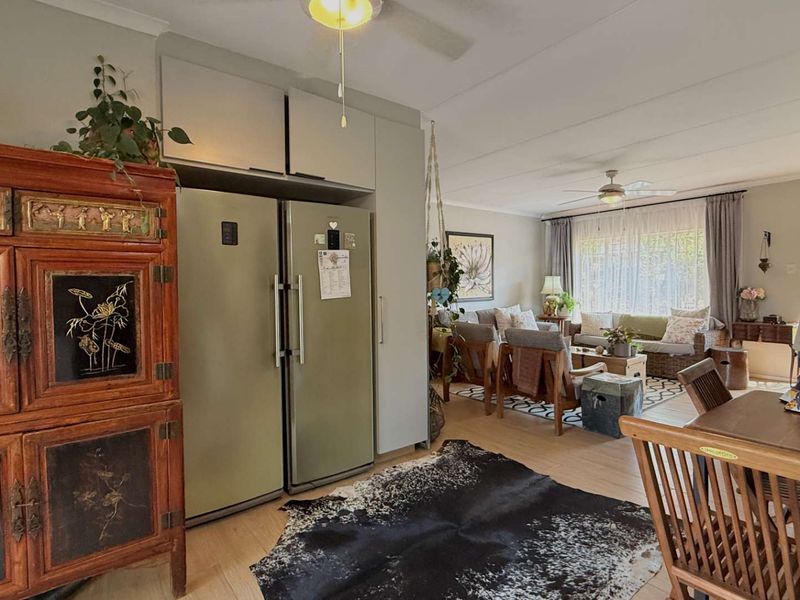 Open plan living and dining area featuring laminate flooring, ceiling fans, and built-in cabinetry, creating a functional and connected living space.
