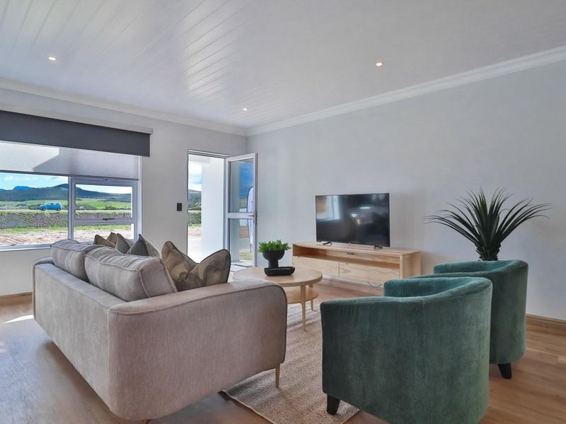 A bright and modern living room featuring laminate flooring, recessed downlighting, and a tongue and groove ceiling with direct access to the outdoors.