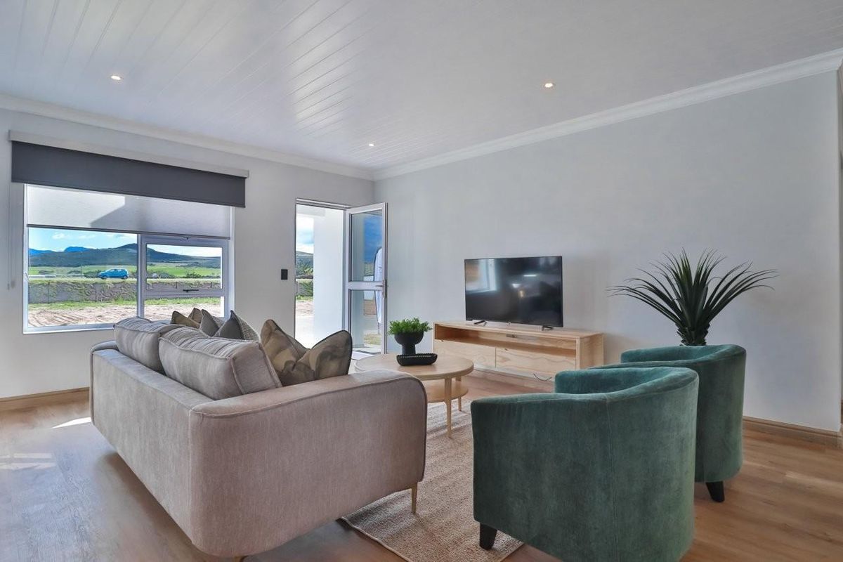 A bright and modern living room featuring laminate flooring, recessed downlighting, and a tongue and groove ceiling with direct access to the outdoors.