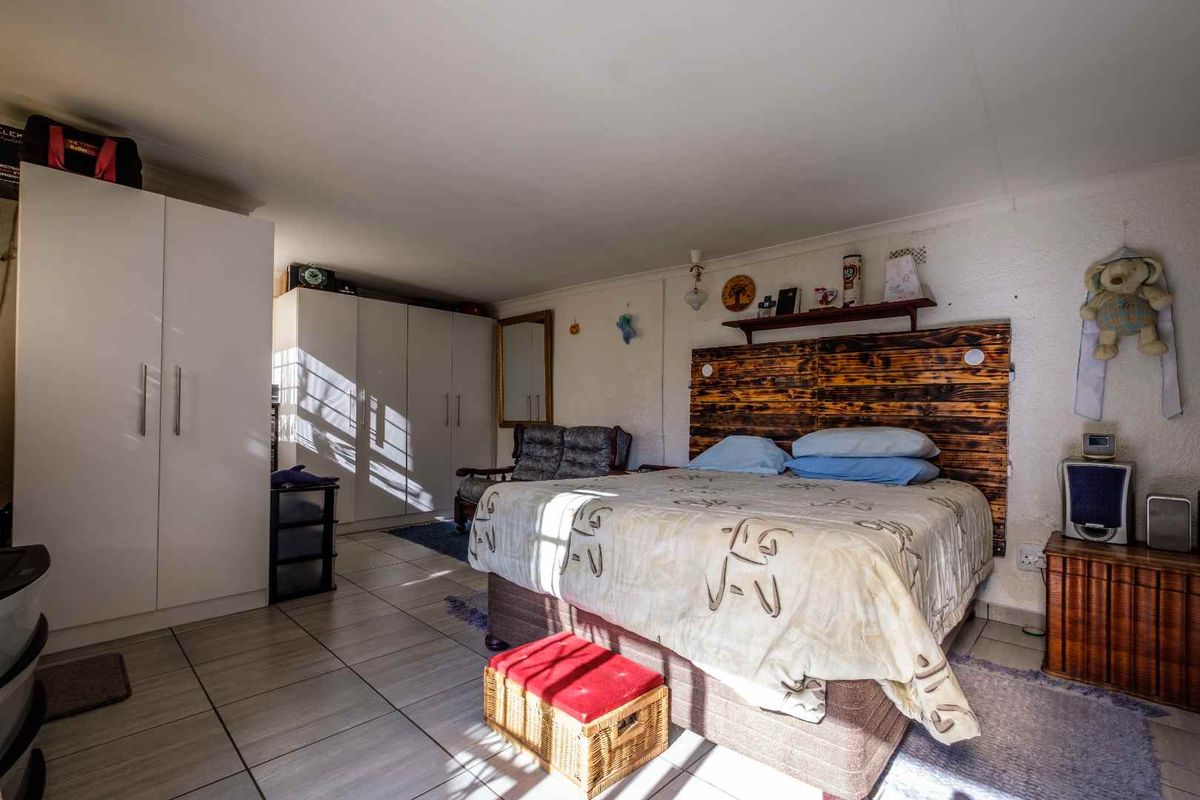 A spacious bedroom featuring tiled flooring and built-in cupboards, offering a functional layout with ample storage space.