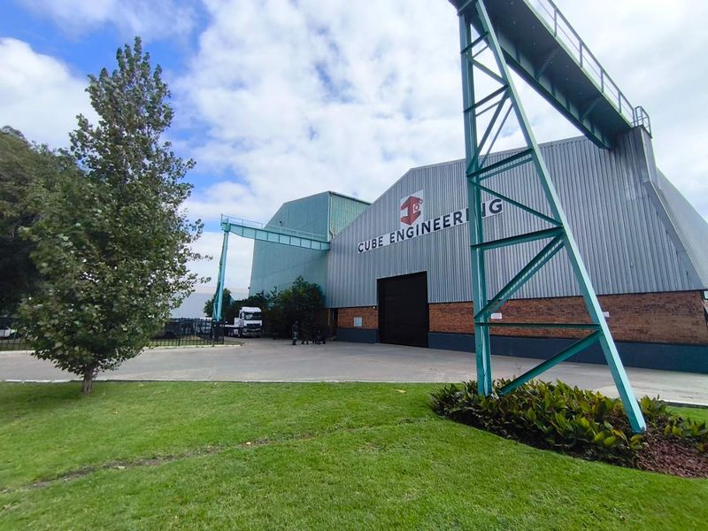 Front exterior view of an industrial engineering facility featuring corrugated metal cladding, brick base, and an integrated gantry crane structure.