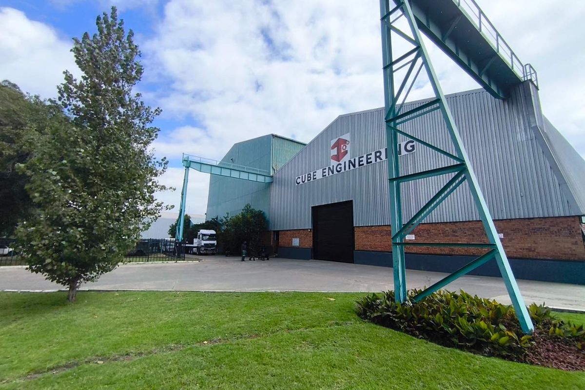 Front exterior view of an industrial engineering facility featuring corrugated metal cladding, brick base, and an integrated gantry crane structure.