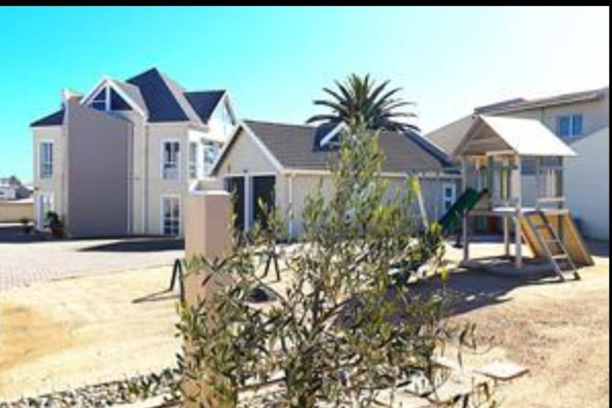 Rear view of the property featuring a paved driveway, double garage, and landscaped garden area.