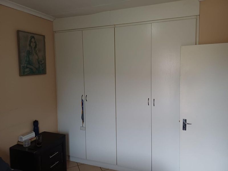 A bedroom featuring white built-in cupboards and tiled flooring, providing functional storage space within the room.