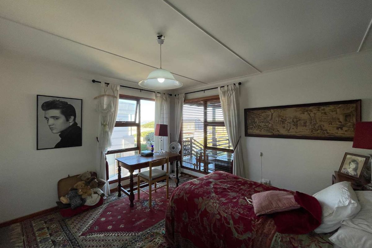A bedroom featuring large windows with natural light, wooden window frames, and direct access to an outdoor balcony area.
