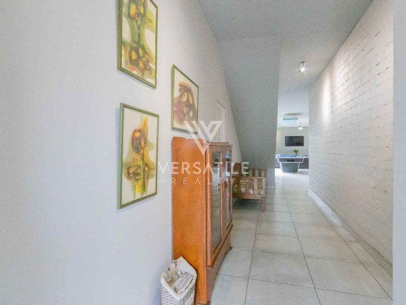 A long hallway featuring tiled flooring and a textured painted brick wall, leading towards an open living area.