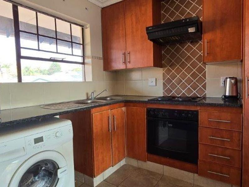 Functional kitchen featuring wooden cabinetry, granite countertops, built-in oven with extractor fan, and tiled backsplash, offering a practical layout for daily use.