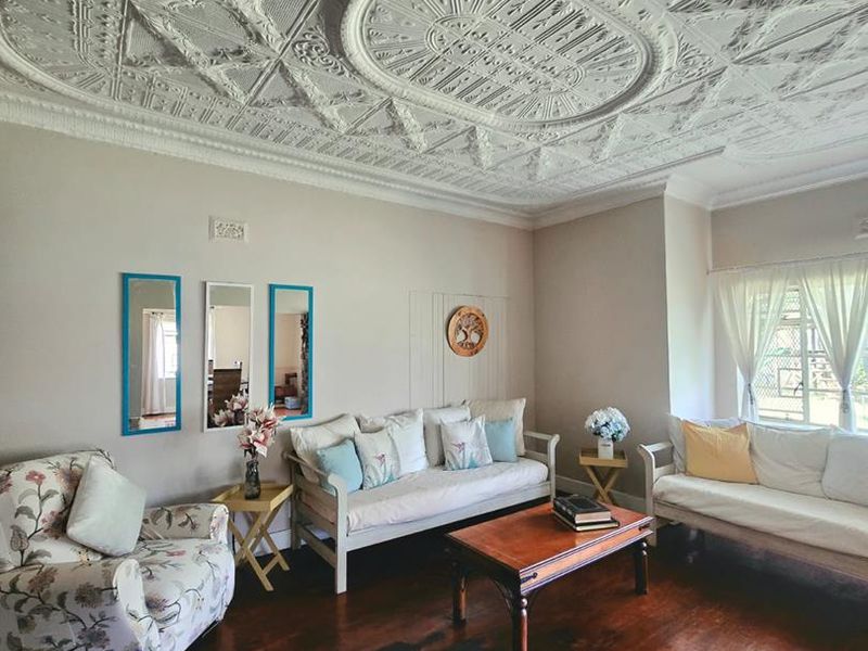 Spacious living room featuring a characterful ornate pressed metal ceiling and original hardwood flooring, offering a classic architectural aesthetic.