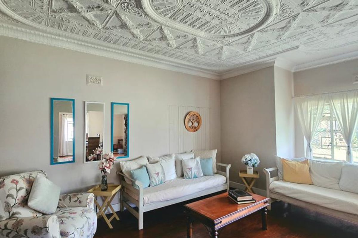 Spacious living room featuring a characterful ornate pressed metal ceiling and original hardwood flooring, offering a classic architectural aesthetic.