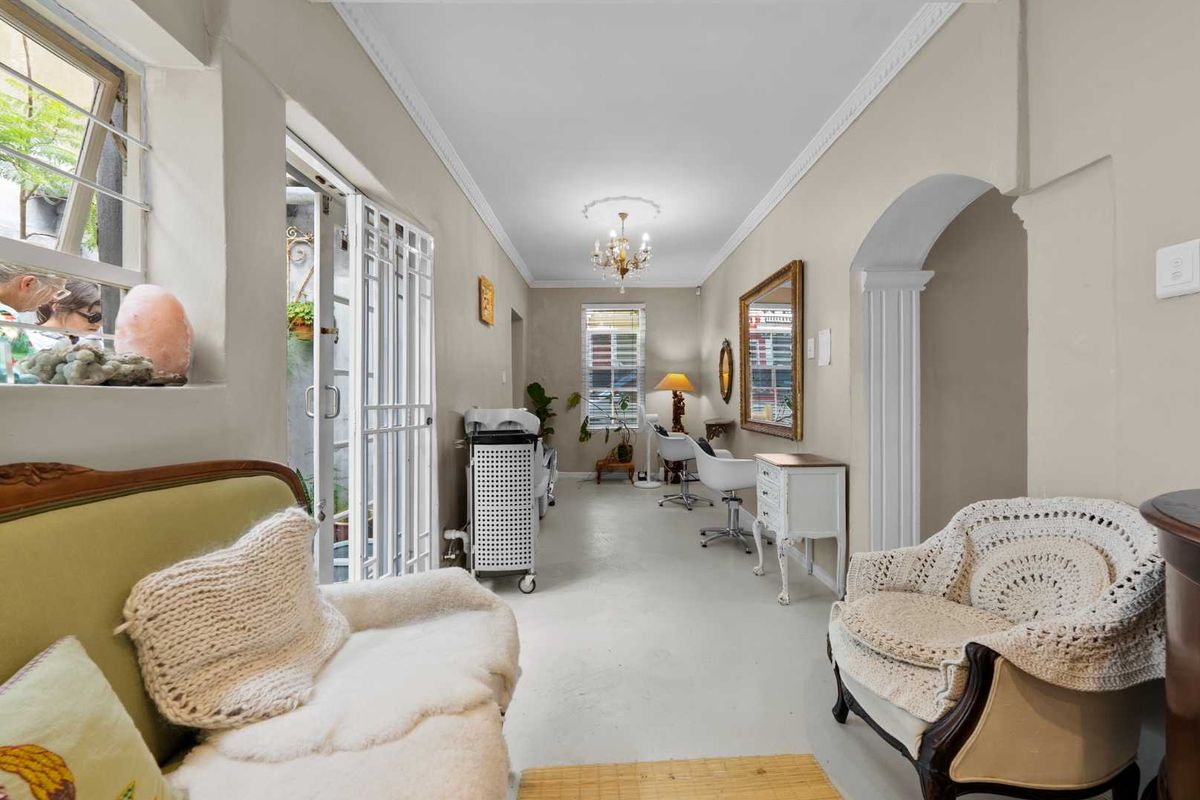 A bright living area featuring classic crown molding, a ceiling rose, and an elegant archway leading to adjacent spaces.