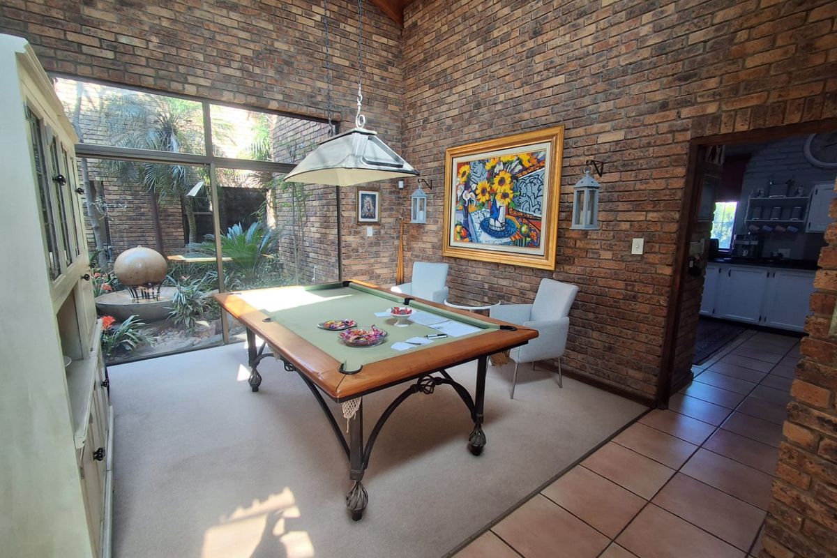 Spacious living area featuring striking exposed brick walls, vaulted ceilings, and large windows overlooking a private courtyard, creating a warm and inviting atmosphere.