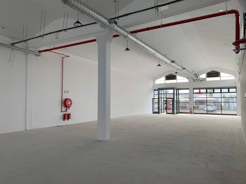 Spacious open-plan retail unit featuring high ceilings with exposed ducting, polished concrete floors, and large glass frontage for excellent natural light.