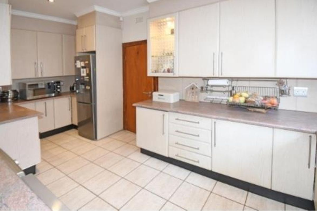 A functional kitchen featuring light-toned laminate cabinetry, ample countertop workspace, and tiled flooring, offering a clean and practical layout for daily use.