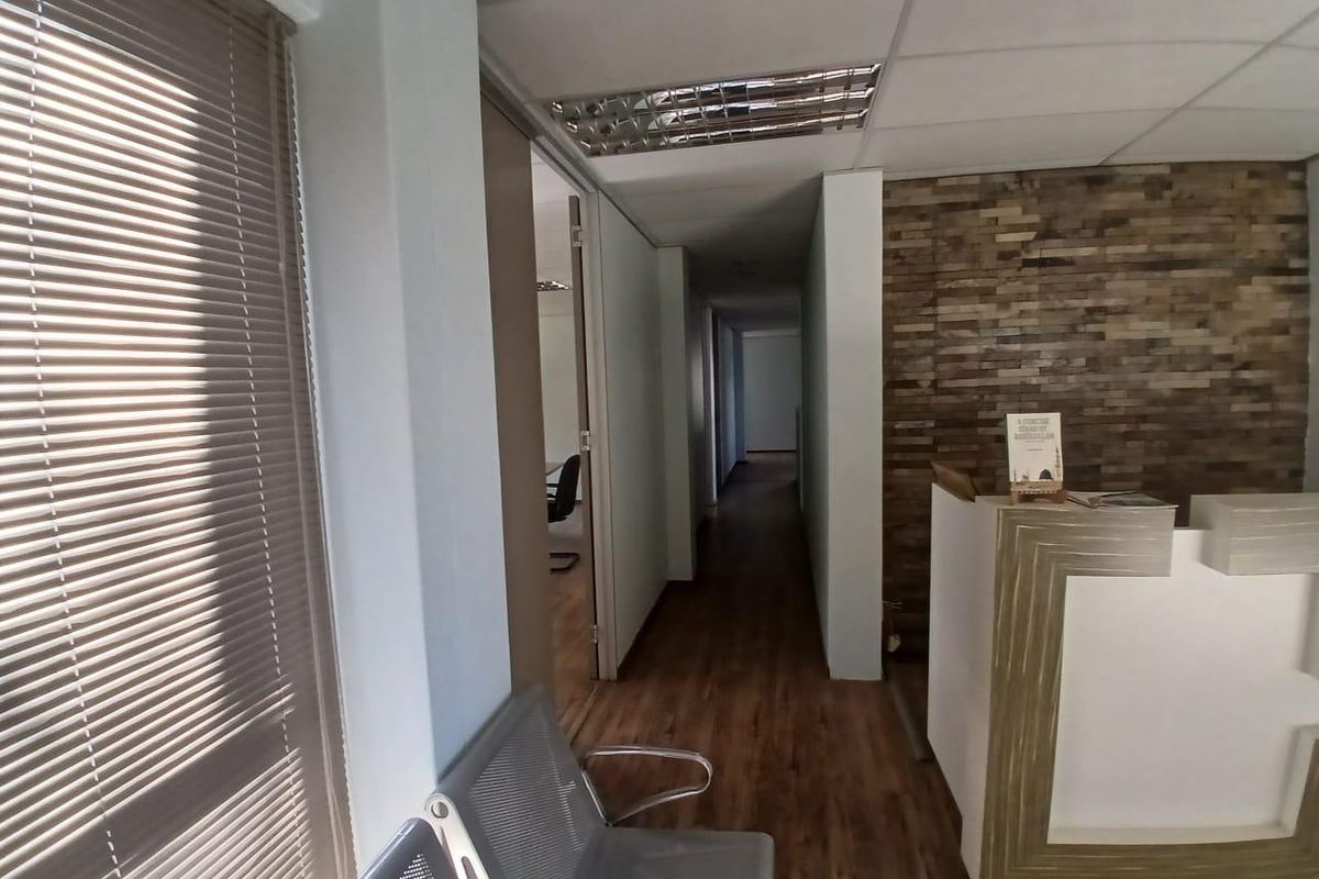 A professional office reception area featuring a stone veneer accent wall, laminate flooring, and a built-in reception desk leading into a central hallway.