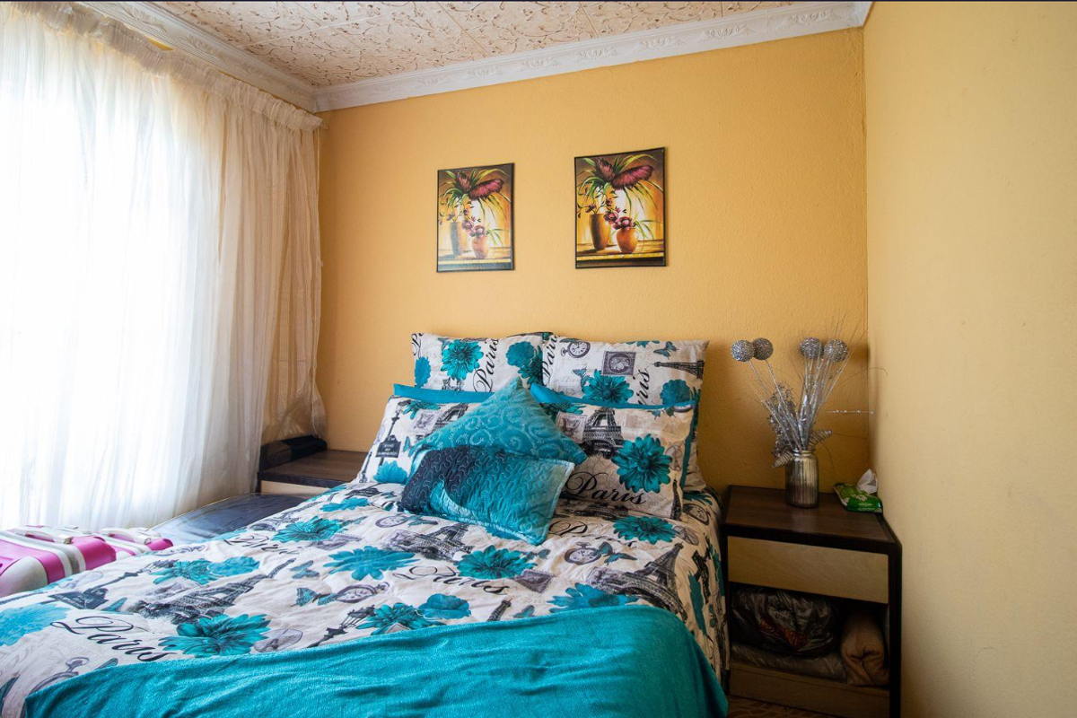 A bedroom featuring textured ceiling detailing, coving, and a large window with curtain rails, providing a functional space for rest.