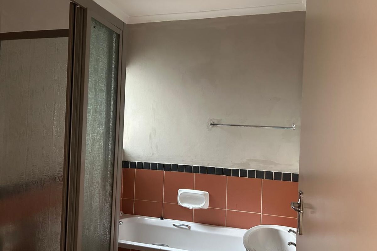 A bathroom featuring a bathtub, pedestal basin, and shower enclosure, currently requiring wall finishing and cosmetic updates to complete the space.