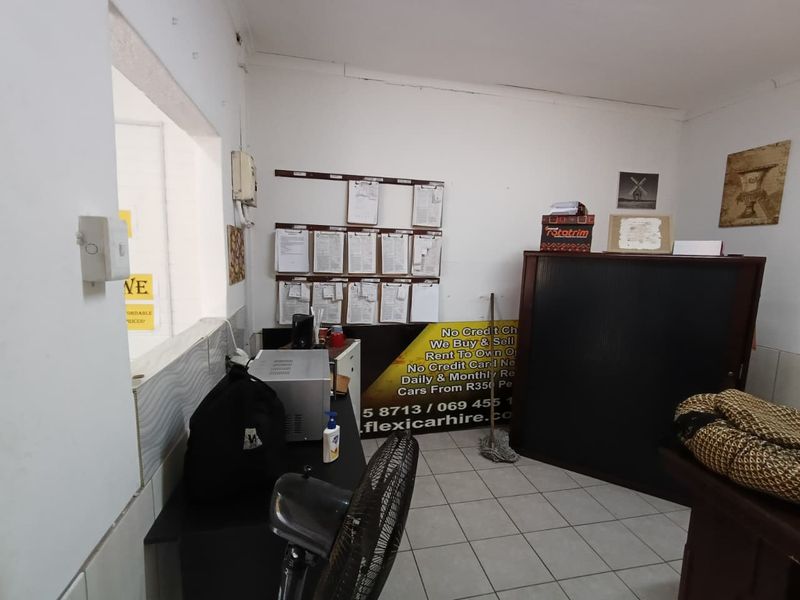 A functional office space featuring tiled flooring and a service window, currently utilized as a reception or administrative area.