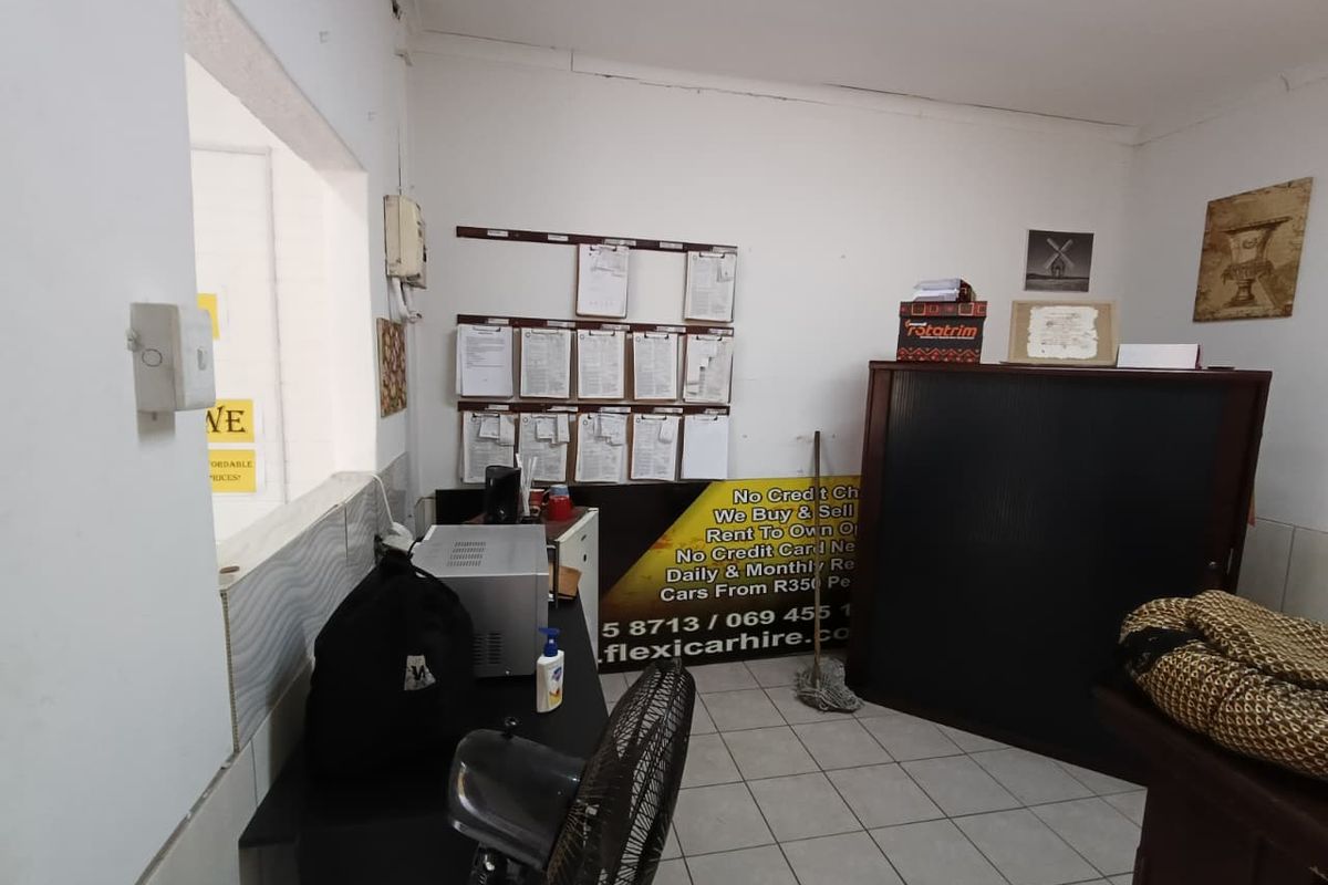 A functional office space featuring tiled flooring and a service window, currently utilized as a reception or administrative area.