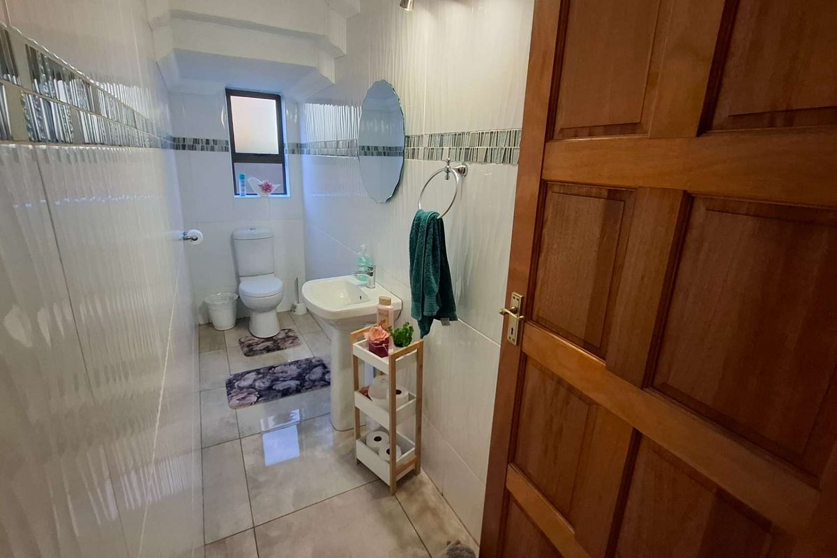A compact bathroom featuring tiled walls and flooring, a pedestal basin, and a standard toilet.
