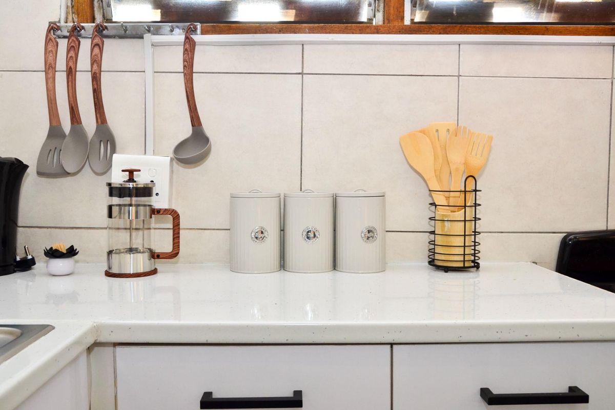 A clean kitchen workspace featuring a white stone countertop, tiled backsplash, and modern cabinetry hardware.