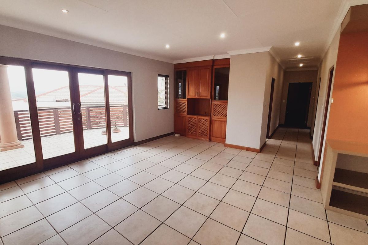 Spacious living area featuring tiled flooring, built-in wooden cabinetry, and large sliding glass doors providing access to an outdoor patio.