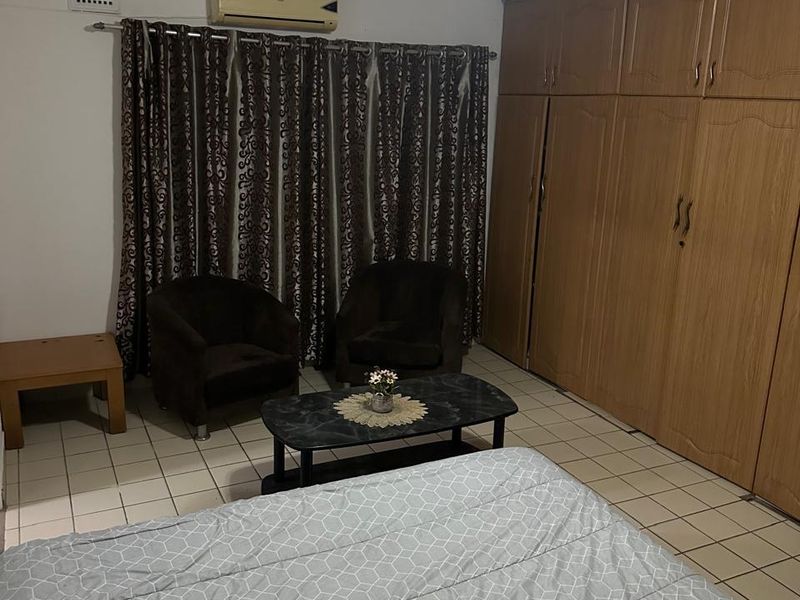 A bedroom featuring tiled flooring, built-in wooden cupboards, and an installed air conditioning unit.