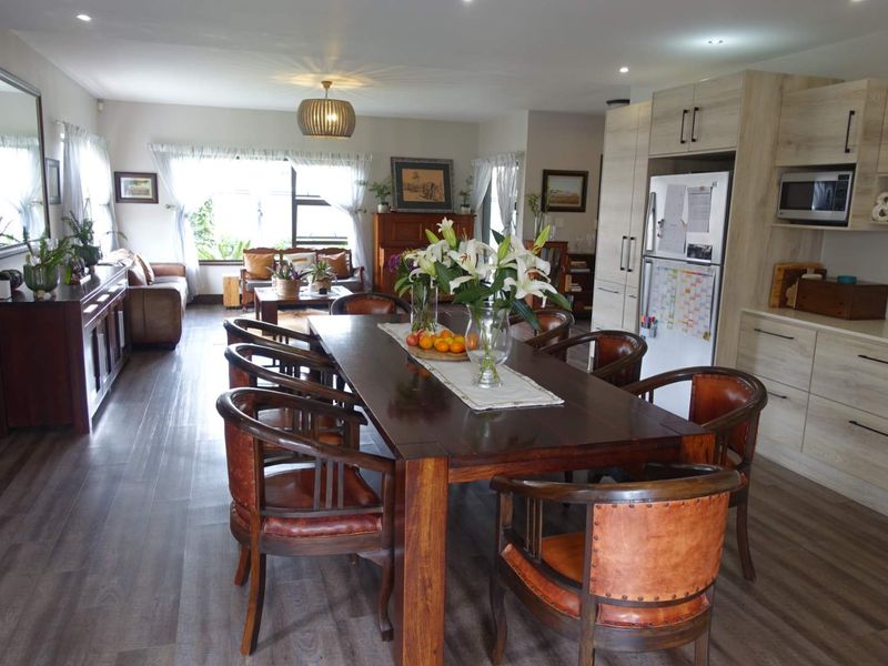 Spacious open-plan living and dining area featuring modern laminate flooring, recessed lighting, and a functional kitchen with integrated cabinetry.