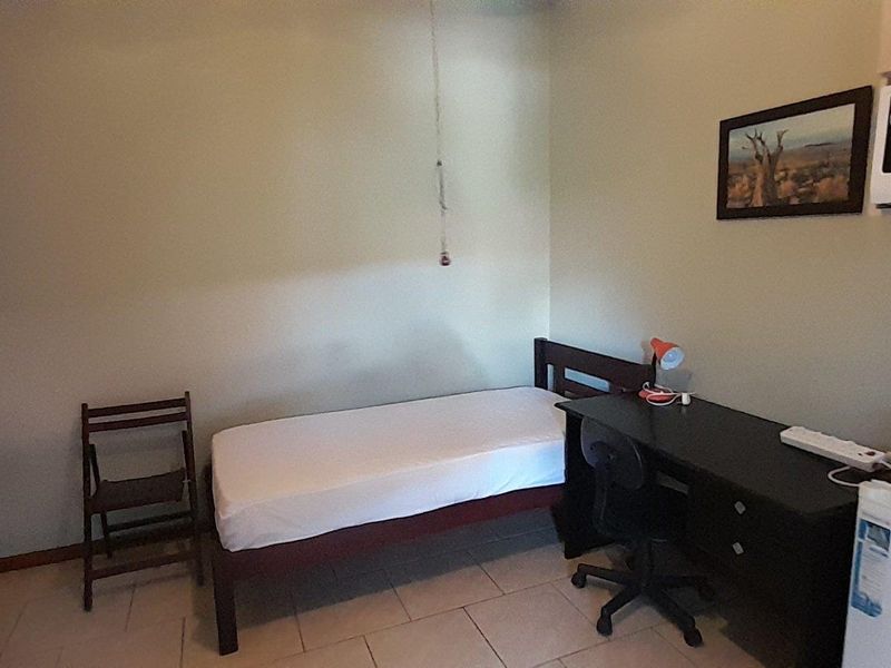 A functional bedroom featuring tiled flooring and a built-in wardrobe, providing a practical living space.