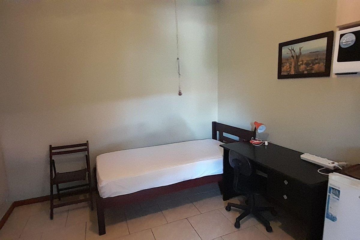 A functional bedroom featuring tiled flooring and a built-in wardrobe, providing a practical living space.