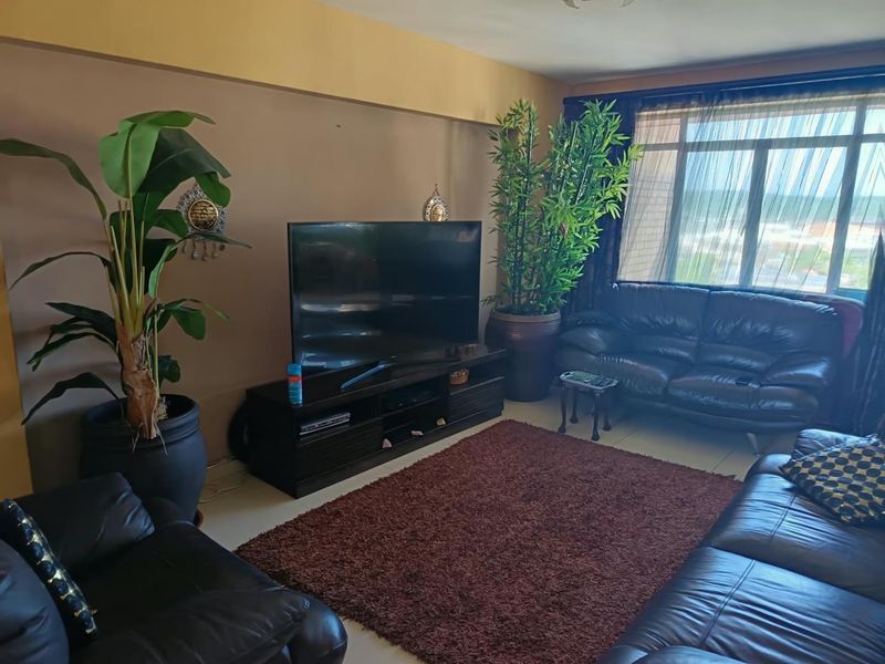 A comfortable living room featuring large windows that provide natural light and tiled flooring throughout the space.