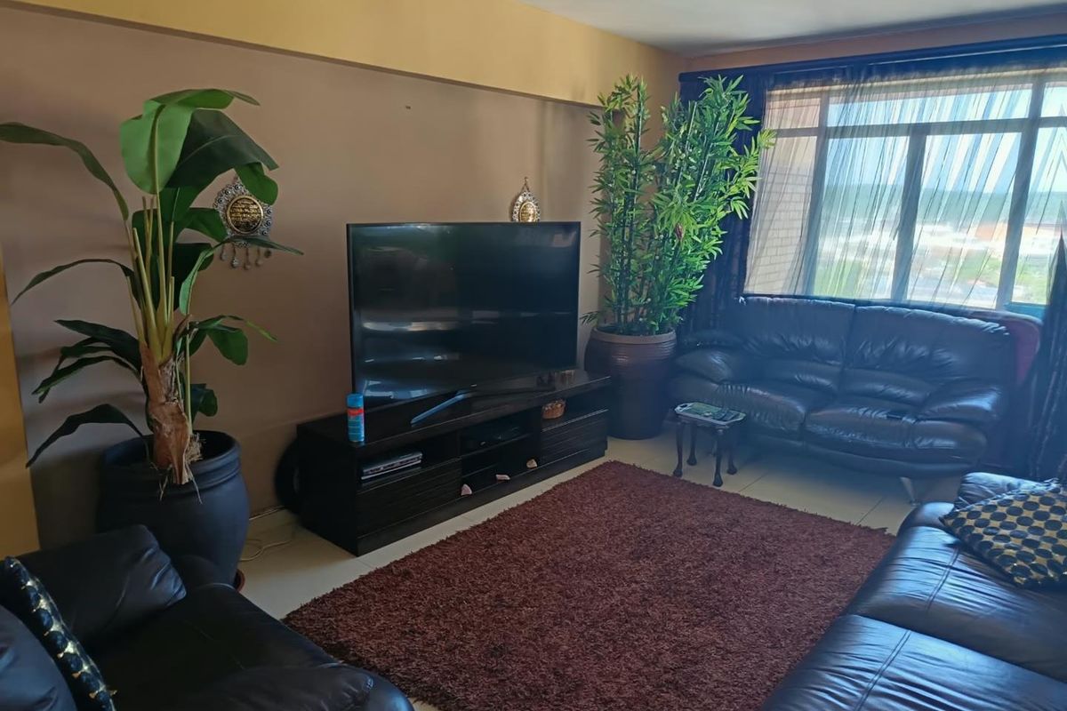 A comfortable living room featuring large windows that provide natural light and tiled flooring throughout the space.