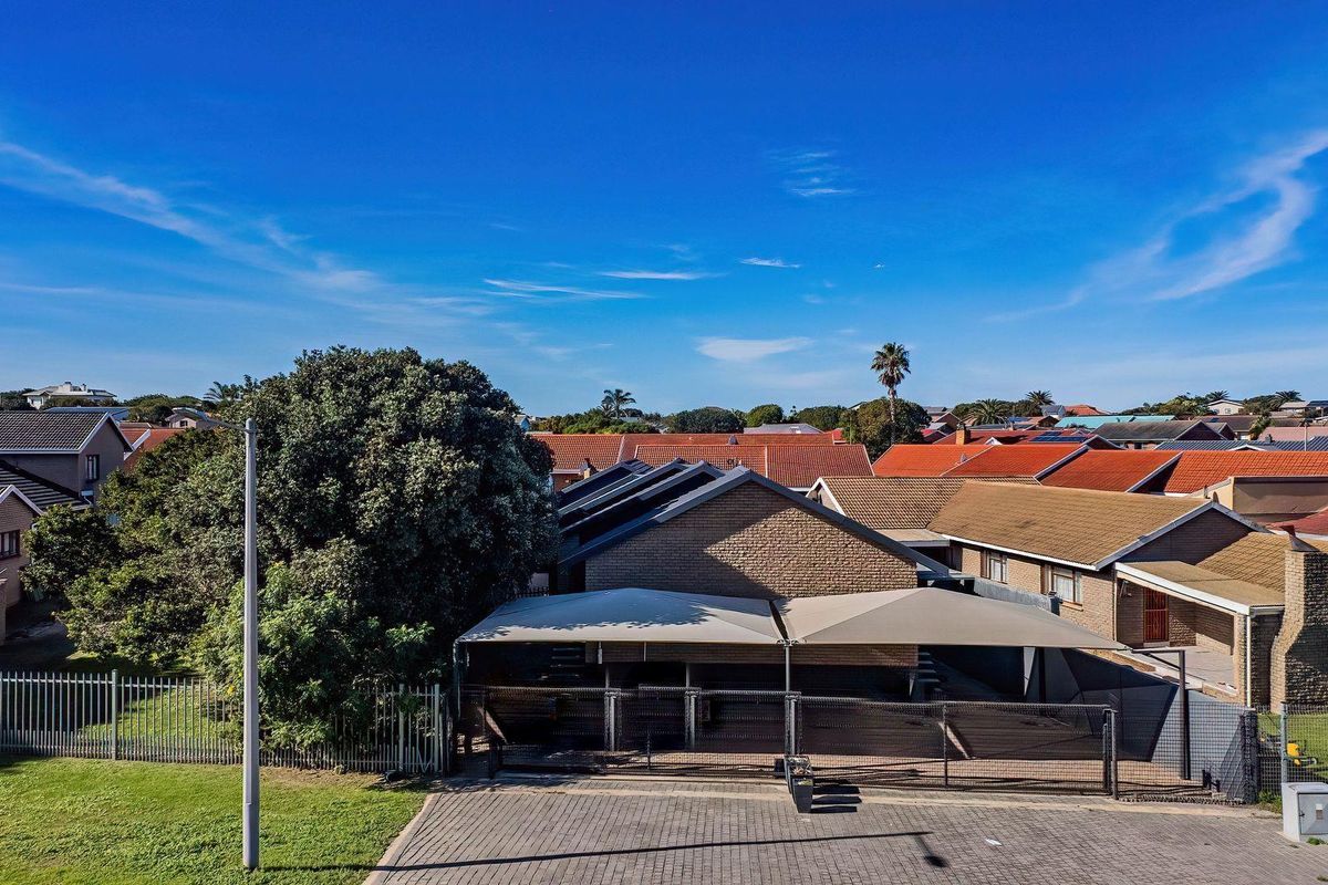 Aerial view of the property showing the paved driveway, shade cloth carport, and surrounding residential neighborhood.