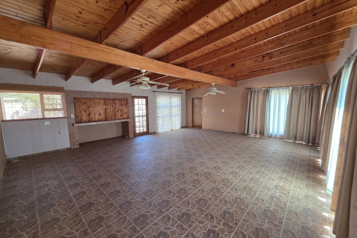 Spacious living area featuring exposed timber beam ceilings, tiled flooring, and a built-in bar counter with wooden cabinetry.