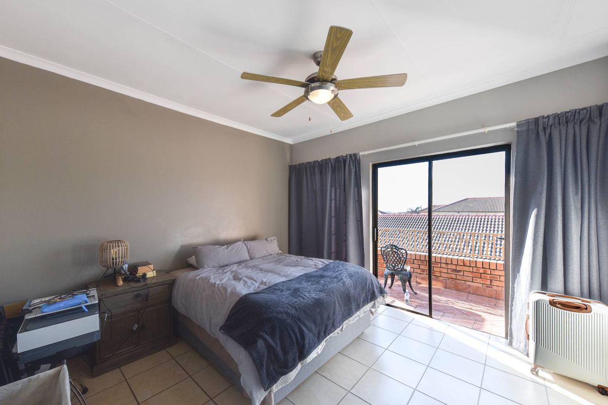 A bedroom featuring tiled flooring, a ceiling fan, and a sliding glass door providing access to an outdoor balcony area.
