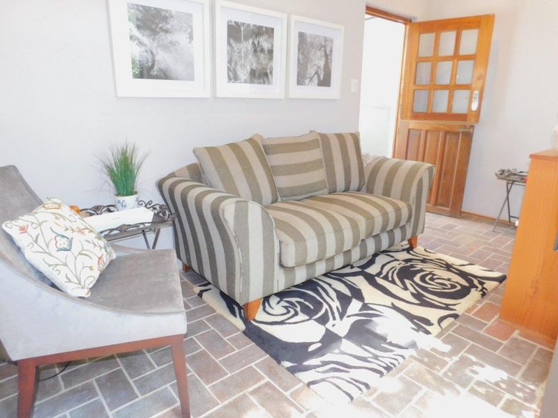 A cozy living area featuring traditional brick tile flooring and a timber-framed glass door leading to the exterior.