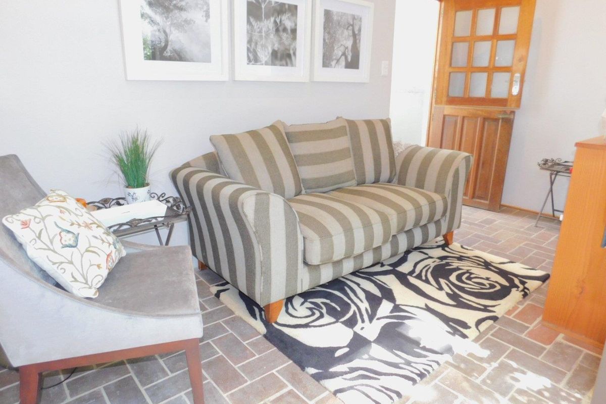 A cozy living area featuring traditional brick tile flooring and a timber-framed glass door leading to the exterior.