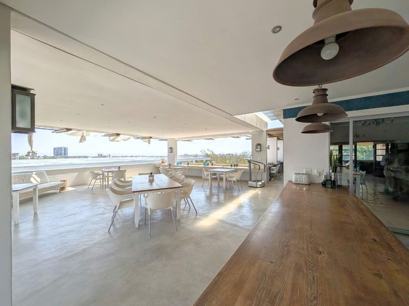 Spacious covered patio featuring polished concrete floors, recessed lighting, and a built-in wooden counter, offering an open-air dining area with expansive views.