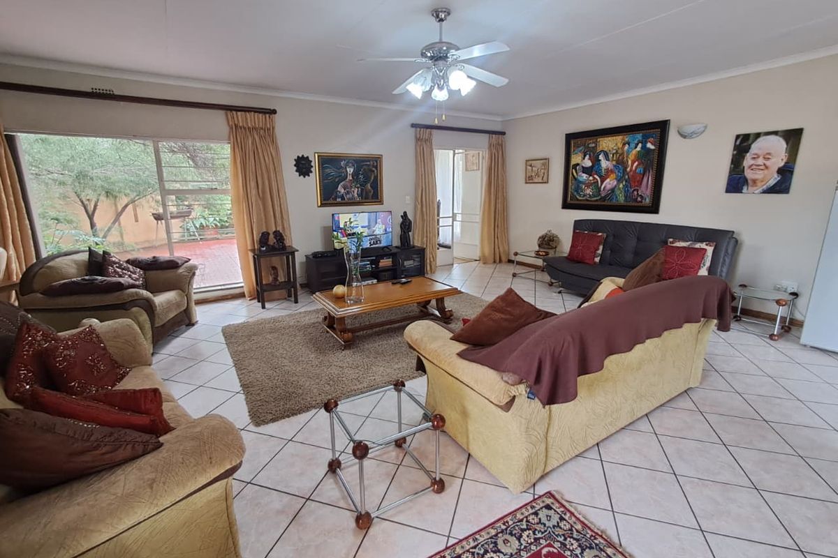 Spacious living room featuring tiled flooring, a ceiling fan, and large sliding glass doors providing natural light and access to the outdoor area.
