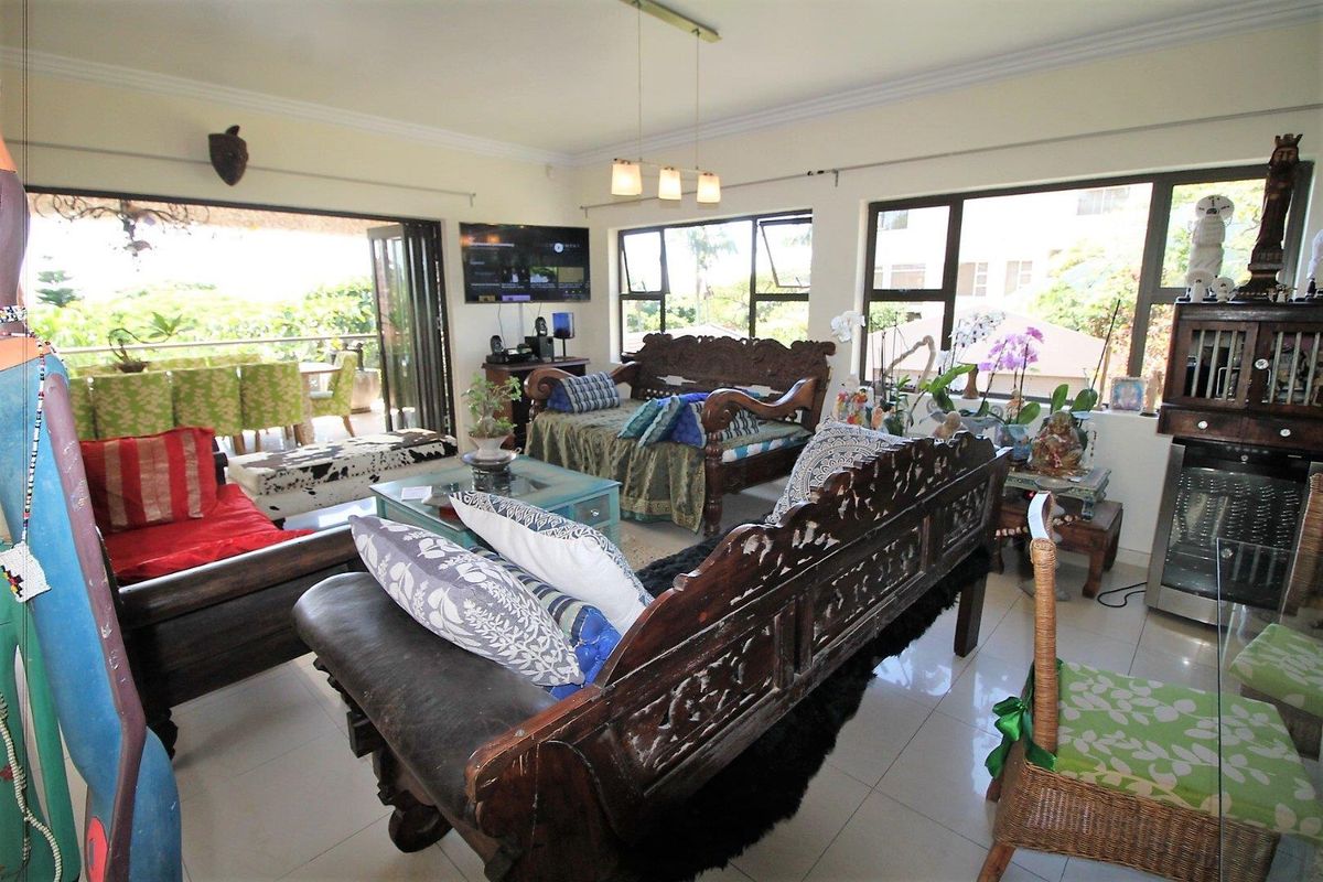 Spacious living room featuring tiled flooring, modern bi-fold doors leading to an outdoor patio, and large windows providing ample natural light.