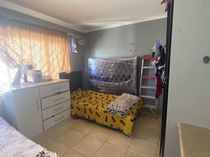 A bedroom featuring tiled flooring and a built-in cupboard, providing functional storage space within the apartment.