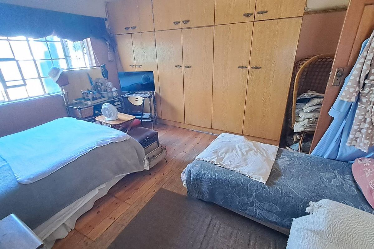 A bedroom featuring built-in wooden cupboards and timber flooring, offering a functional layout with natural light from the window.