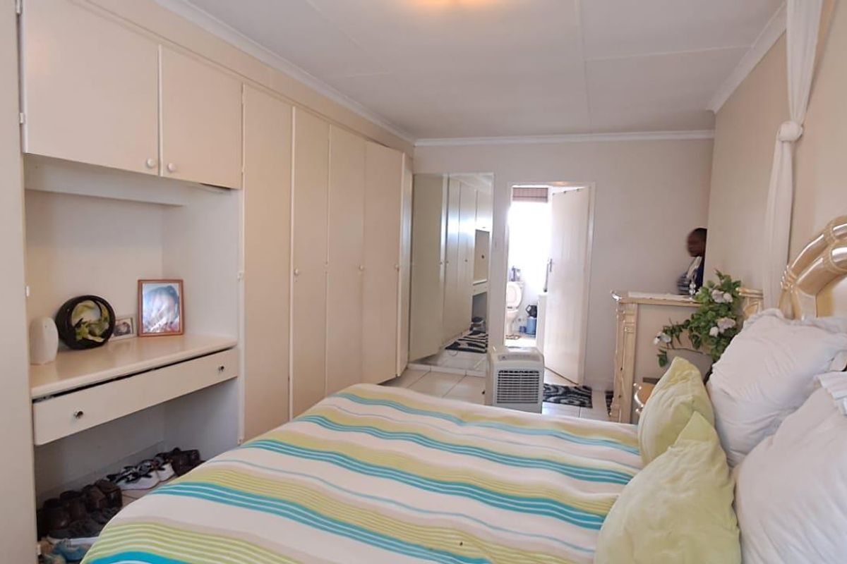 A bedroom featuring extensive built-in cabinetry with integrated vanity space and direct access to an en-suite bathroom.