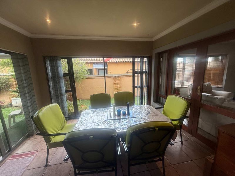 A covered patio area featuring tiled flooring, recessed lighting, and large sliding glass doors providing access to the garden.