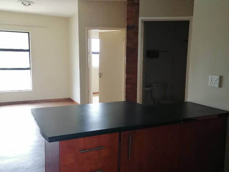 Open plan living area featuring a kitchen island with built-in cabinetry, an exposed brick pillar, and views into adjacent rooms.