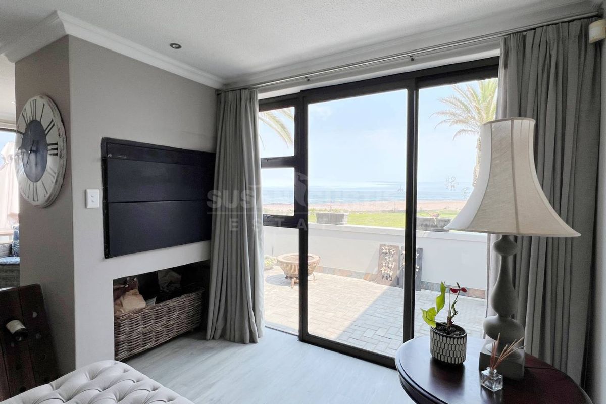 A bright living room featuring large sliding glass doors that open onto a paved patio with scenic ocean views.