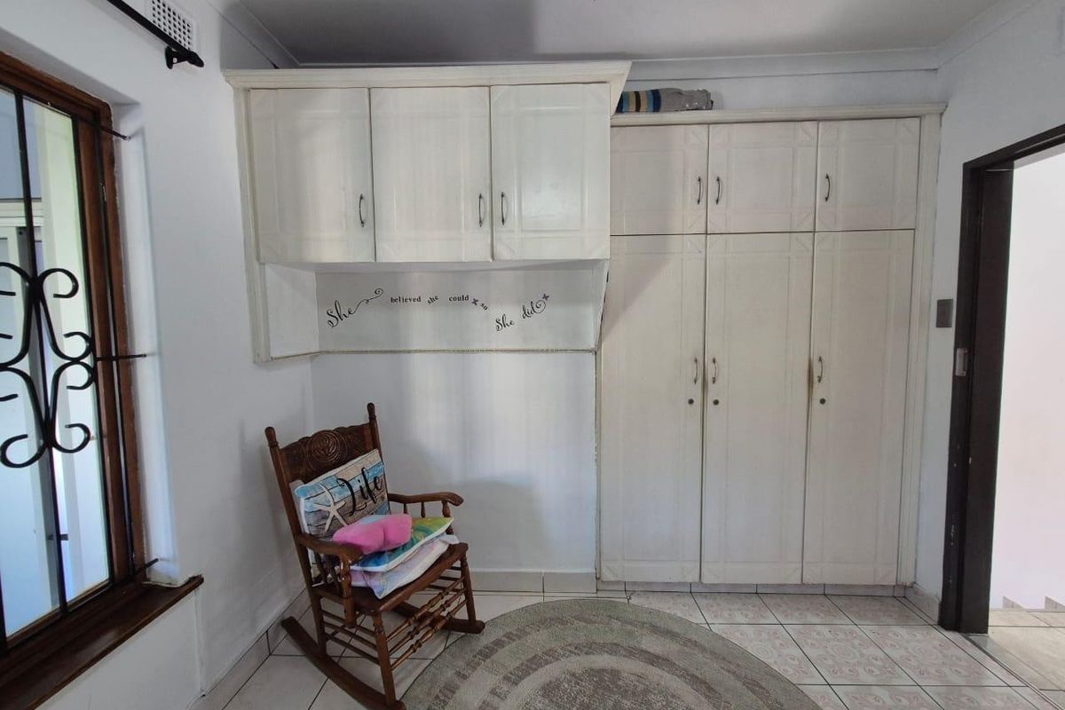 Bedroom featuring built-in white cabinetry, tiled flooring, and a window with a security gate.
