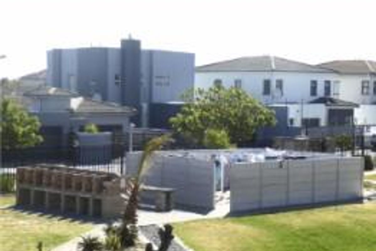 Outdoor communal area featuring a brick braai facility and paved space enclosed by precast concrete walling within a residential complex.