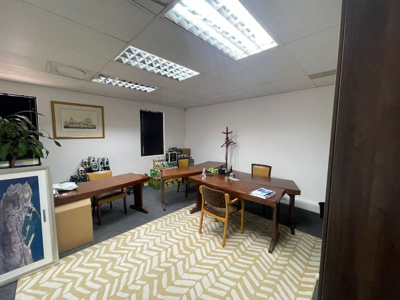 A functional office space featuring suspended ceilings with recessed lighting, carpeted flooring, and window blinds, providing a practical work environment.