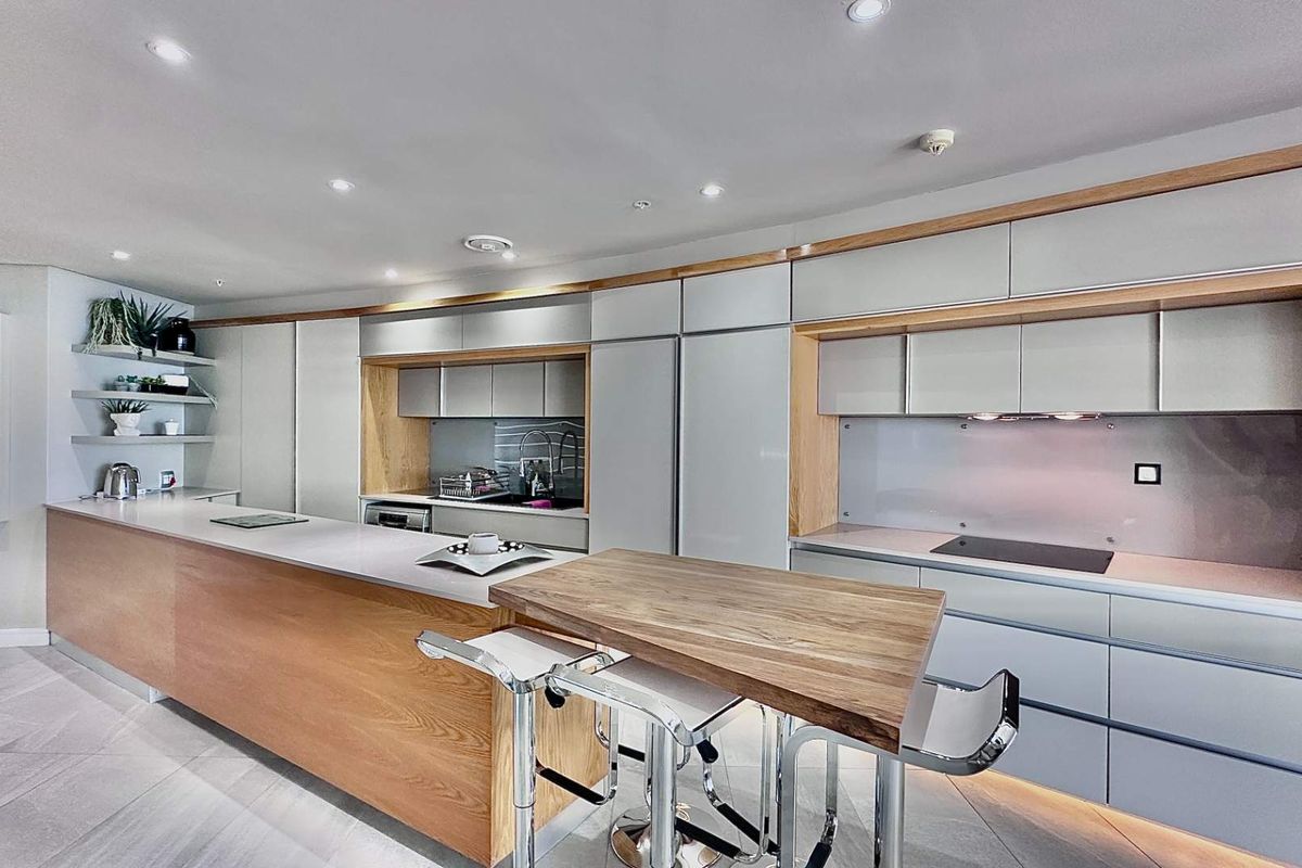 Modern kitchen featuring sleek cabinetry, integrated appliances, a large island with a breakfast bar, and recessed lighting.