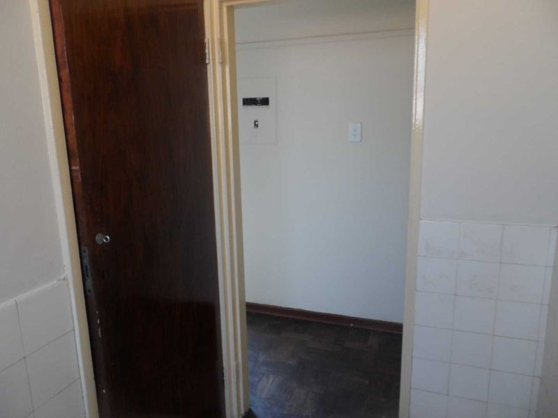 A functional hallway space featuring parquet flooring, a wooden door, and a wall-mounted electrical distribution board.